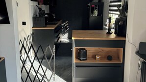 Une cuisine moderne avec un plan de travail en bois, des appareils électroménagers noirs et un réfrigérateur noir.