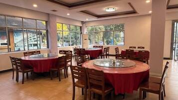 A dining area with round tables, chairs, and a central glass-top table.