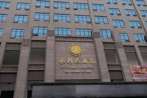 Un edificio de varios pisos con un cartel de hotel destacado, varias ventanas y una entrada visible.
