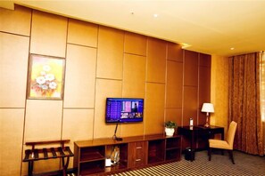 A hotel room with a flat-screen TV mounted on the wall, a small table with a lamp, a chair, and a bench with a wine rack. - Yongli Hotel (Yuechi)