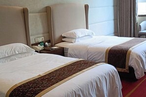Habitación de hotel con dos camas, una alfombra roja y una mesita de noche con teléfono y lámpara.