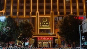 A hotel with a prominent sign in the center, surrounded by trees and a metal fence. - Yongli Hotel (Yuechi)