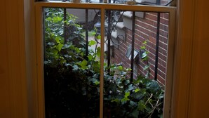 A window with a view of a brick building and a bicycle parked outside.