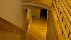 A wooden staircase with a handrail leading to an upper floor.