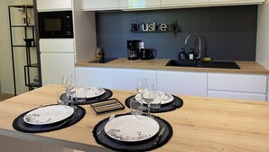 A modern kitchen with white cabinets, a black microwave, a coffee maker, and a sink.