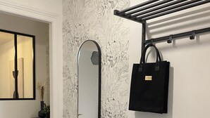 A modern bathroom with a mirror, a black towel rack, and a black bag hanging on it.