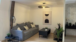 A modern living room with a grey sofa, a small black side table, and a floor lamp.