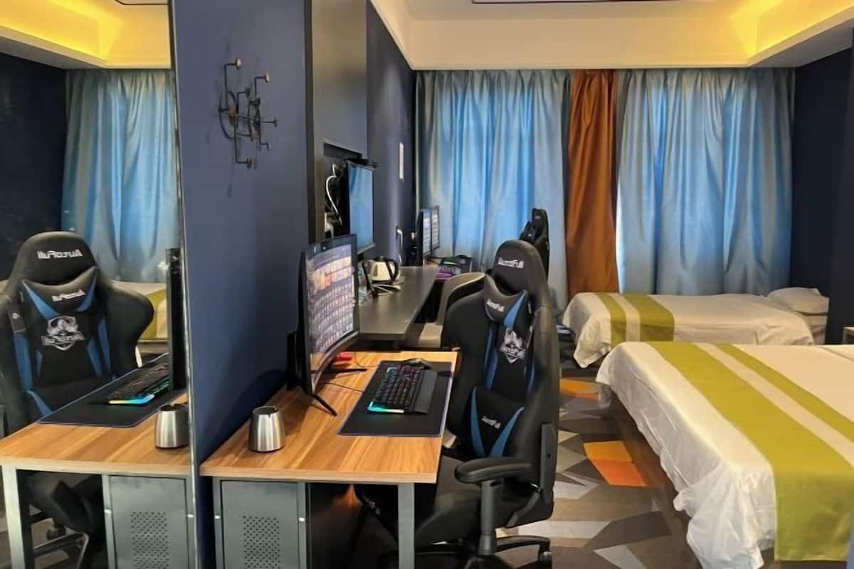 A hotel room with two beds, a desk with a computer and a chair, and a TV.