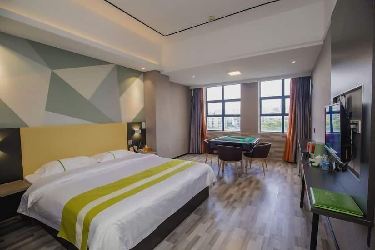 A hotel room with a bed, a desk with a computer, a pool table, and a TV.