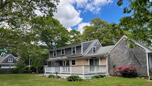 A two-story house with a front porch, a garage, and a well-maintained lawn. - Close to BEACH! Falmouth / Falmouth Heights 4Bdr-2Ba. 2025 Renovation Large Deck (Falmouth)