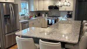 A modern kitchen with a central island, stainless steel appliances, and pendant lighting. - Close to BEACH! Falmouth / Falmouth Heights 4Bdr-2Ba. 2025 Renovation Large Deck (Falmouth)