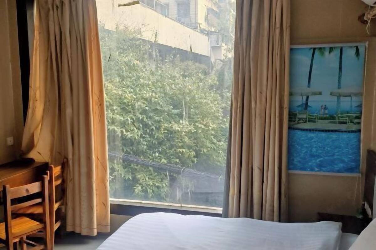 Une chambre d’hôtel avec un lit, un bureau et une fenêtre donnant sur une piscine et un espace verdoyant.