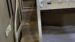 Ένα κρεβάτι με δύο κουκέτες, με ξύλινο πλαίσιο και λευκά κλινοσκεπάσματα.