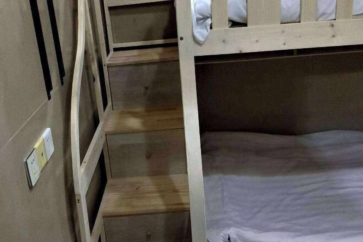 Un lit superposé avec une structure en bois et du linge de lit blanc.
