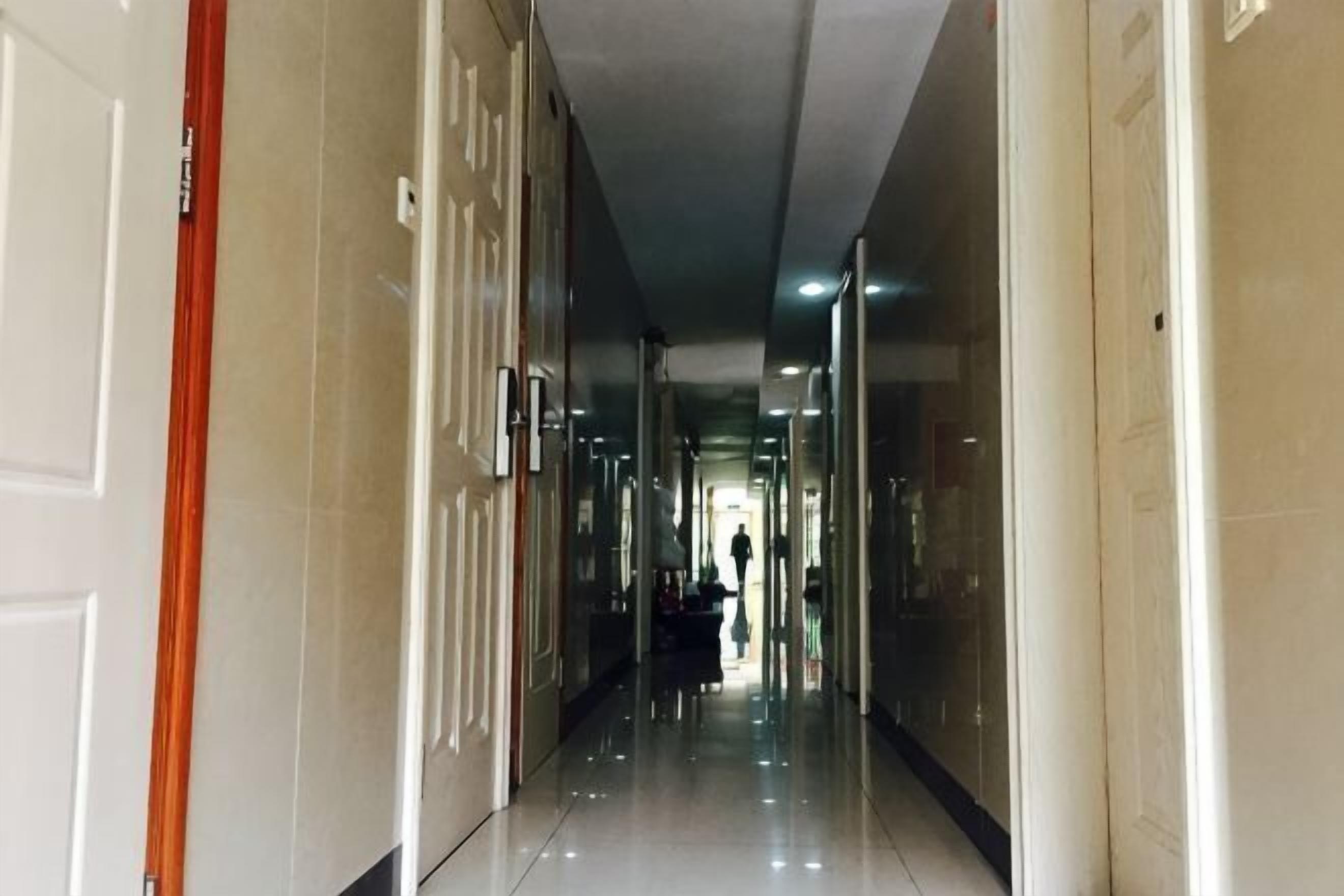 A corridor with doors on both sides, leading to rooms.