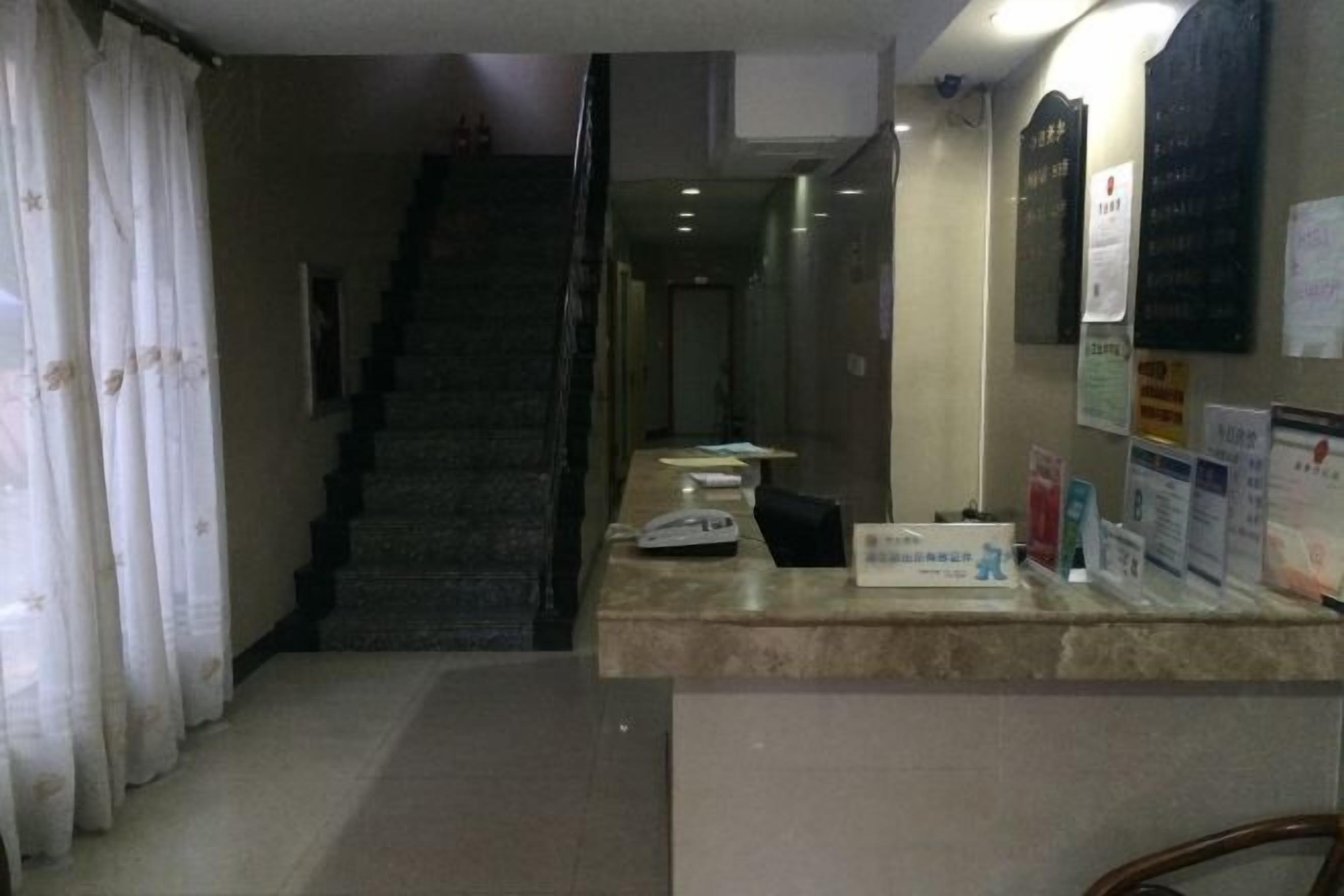 A hotel reception area with a marble counter, a telephone, and informational posters on the wall.