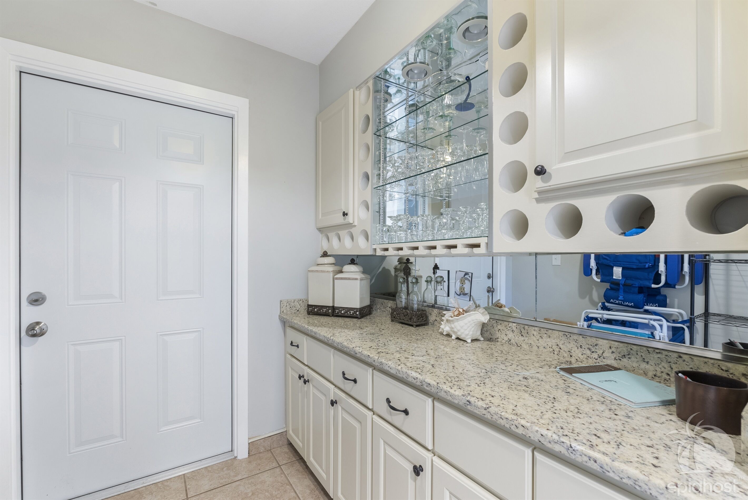 A kitchen with white cabinets, a granite countertop, and a glass-fronted cabinet with shelves.