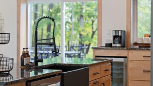 Eine moderne Küche mit einem großen Fenster, einer Kaffeemaschine und Holzschränken.
