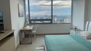 A modern bedroom with a large window, a desk with a chair, a bed, and a TV on a stand.