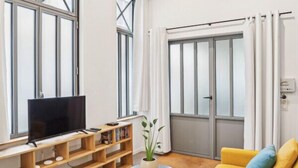 Una sala de estar moderna con un sofá amarillo, un televisor y una estantería de madera.