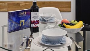 Una mesa de comedor con una botella de vino, un cuenco de fruta y una caja de menú.