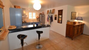 Una cocina moderna con una isla central, taburetes de bar, un refrigerador y un armario de madera.