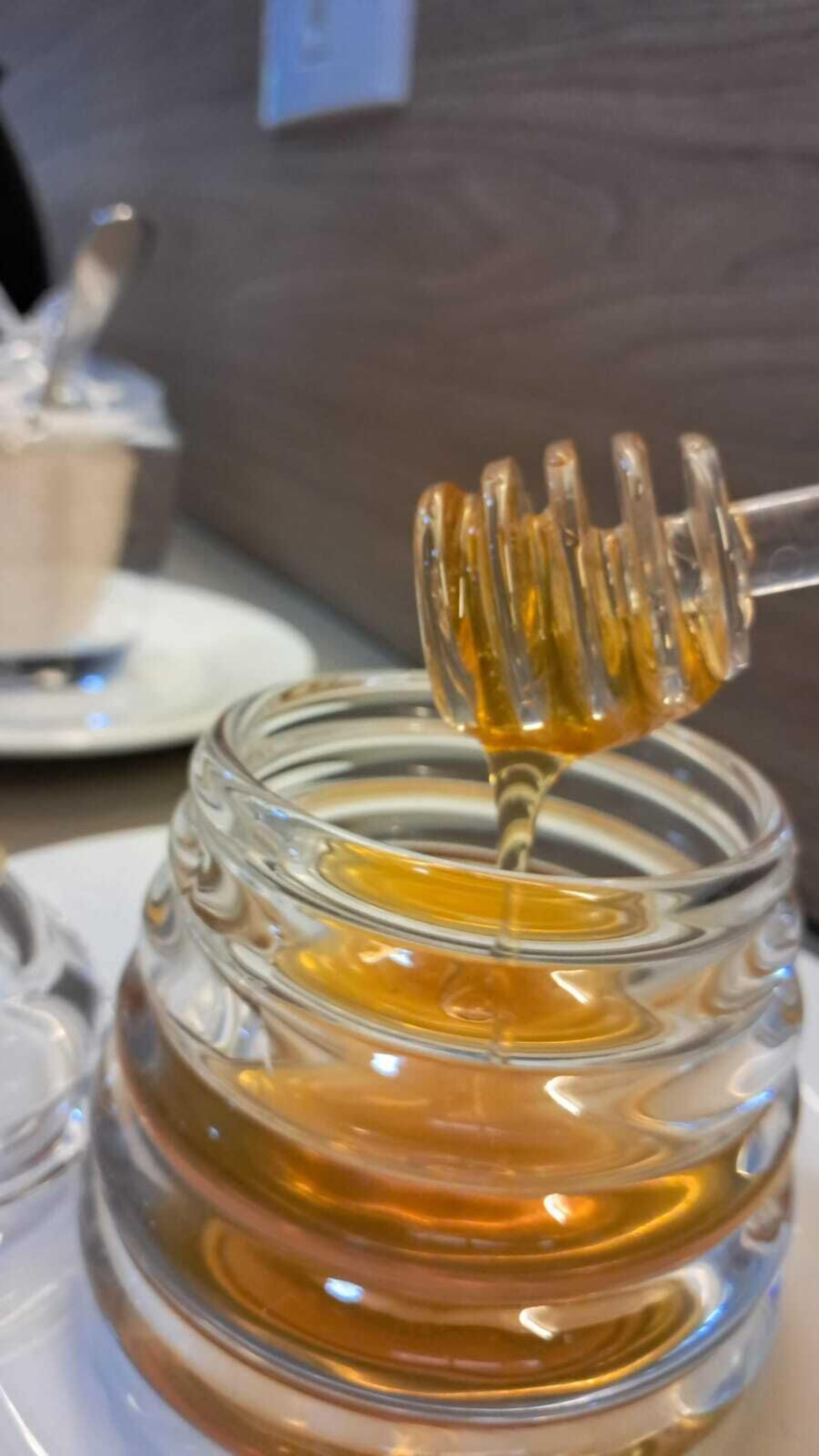 A honey dipper dripping honey from a jar.