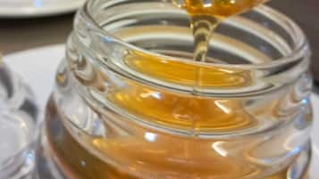 A honey dipper dripping honey from a jar.