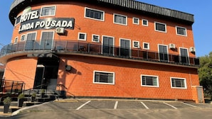 A two-story building with a curved facade, a balcony on the upper floor, and a sign reading "HOTEL LINDA POUSADA". - Hotel Linda (Salto)