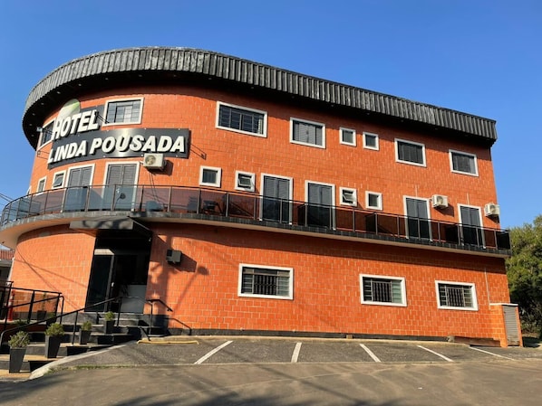 Un immeuble de deux étages doté d’une façade incurvée, d’un balcon à l’étage supérieur et d’une enseigne indiquant « HÔTEL LINDA POUSADA ».