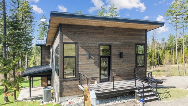 A modern log cabin with large windows, a deck, and a solar panel. - Brand New, Luxury 1-bedroom apartment with AC, 10 Minutes to Downtown Whitefish (Whitefish)