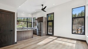 A spacious kitchen with a large island, stainless steel appliances, and a view of a wooded area. - Brand New, Luxury 1-bedroom apartment with AC, 10 Minutes to Downtown Whitefish (Whitefish)