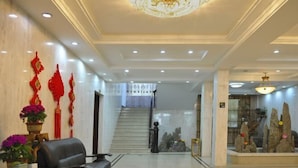 Un vestíbulo con una escalera, una recepción y elementos decorativos.