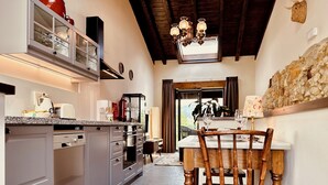 Una cocina con comedor, que incluye una silla de madera, un muro de piedra y una ventana con vistas.