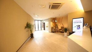 A hotel reception area with a reception desk, a potted plant, and a signboard. - Homeinns Neo Wuhu Wanzhi XinwuDevelopment Zone Hotel (Wuhu)