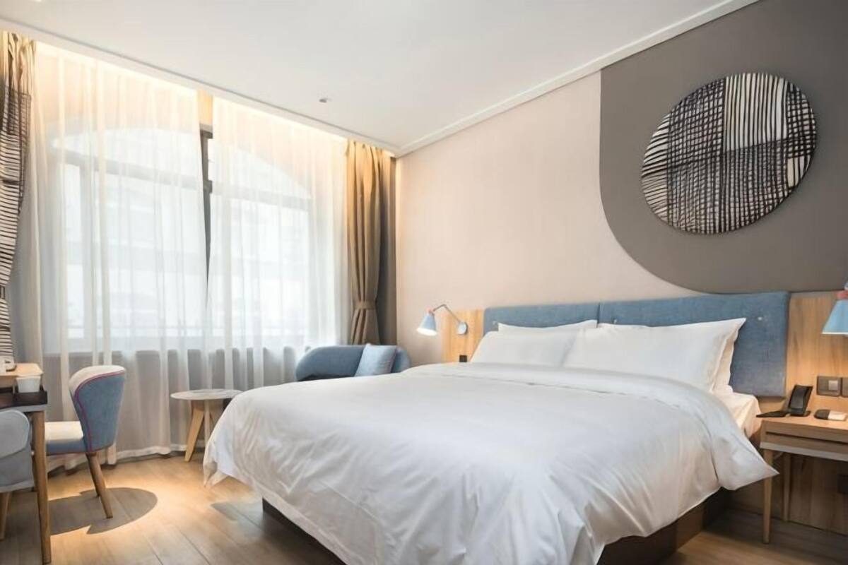 Hotellihuone, jossa on suuri sänky, työpöytä, tuoli ja näkymä ulos.