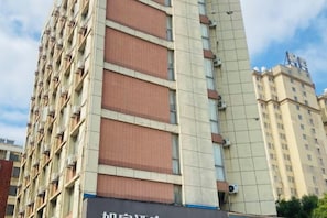 Un edificio de varios pisos con una sección vertical destacada y un letrero con caracteres chinos.