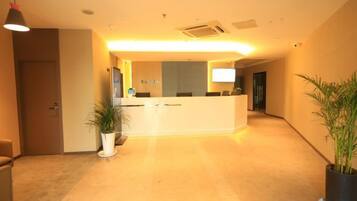 A reception area with a reception desk, a potted plant, and a door leading to another room.
