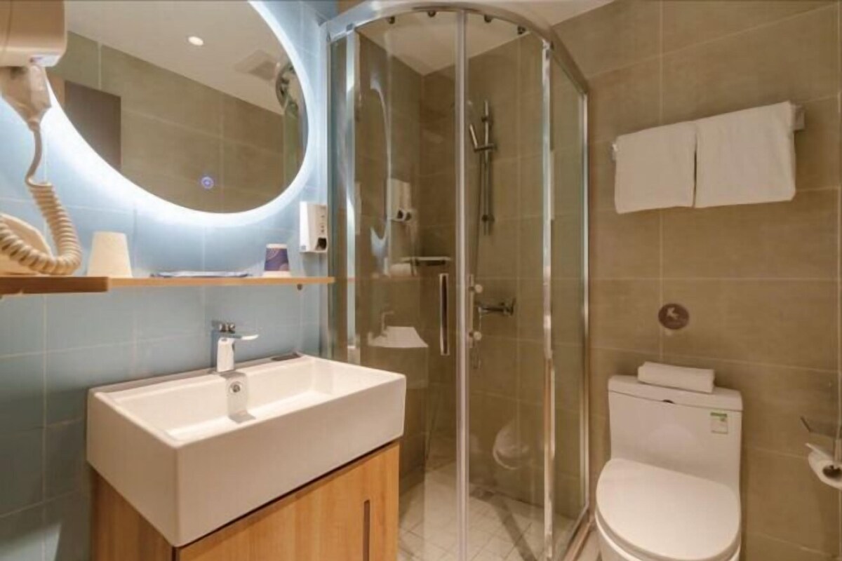 Une salle de bain moderne avec une douche à parois de verre, un lavabo blanc et des toilettes.