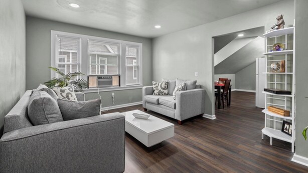 Una sala moderna con un sofá gris, una mesa de centro blanca y una estantería.