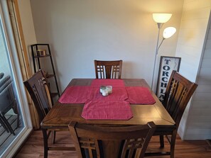 A dining table with a red placemat, wooden chairs, a candle, and a wall-mounted lamp. - Shanty Creek. Reserve Now For Golf and Color Tour Weekend!  Condo Sleeps 8. (Bellaire)