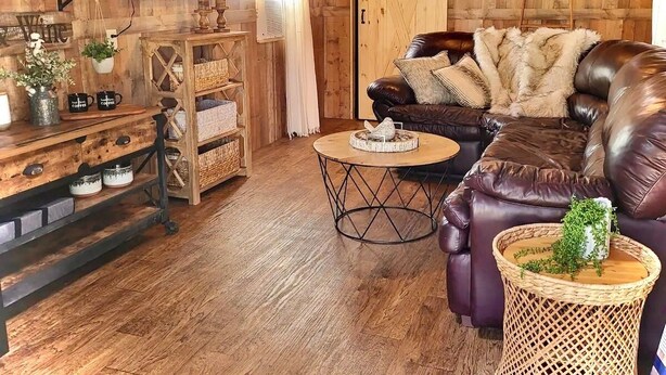 Un salon chaleureux avec un canapé en cuir, une table basse et un meuble TV en bois.