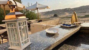 Una terraza con mostrador de piedra, un farol blanco y un plato decorativo.