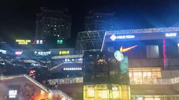 A nighttime cityscape with illuminated signage for various businesses, including a Starbucks.