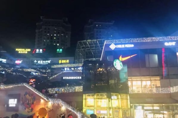 A nighttime cityscape with illuminated signage for various businesses, including a Starbucks. - Mingyue Business Hotel(Huaqiang North subway station store) (Shenzhen)