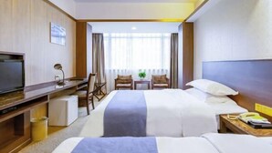 Une chambre d’hôtel avec deux lits, un bureau, une télévision et un petit coin salon avec des chaises et une table.
