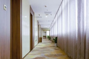 A hotel corridor with a patterned carpet, wooden doors, and a long row of curtains on one side. - Mingyue Business Hotel(Huaqiang North subway station store) (Shenzhen)
