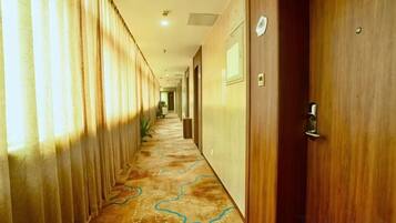 A hotel corridor with wooden doors, a patterned carpet, and a long hallway.