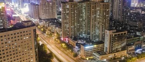 Un paisaje urbano nocturno con rascacielos, calles iluminadas y una autopista.