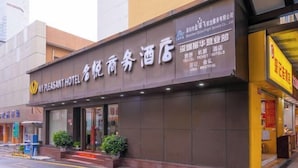 Un hôtel dont l’enseigne est affichée en anglais et en chinois, indiquant qu’il propose des services de voyage et accepte différents modes de paiement.